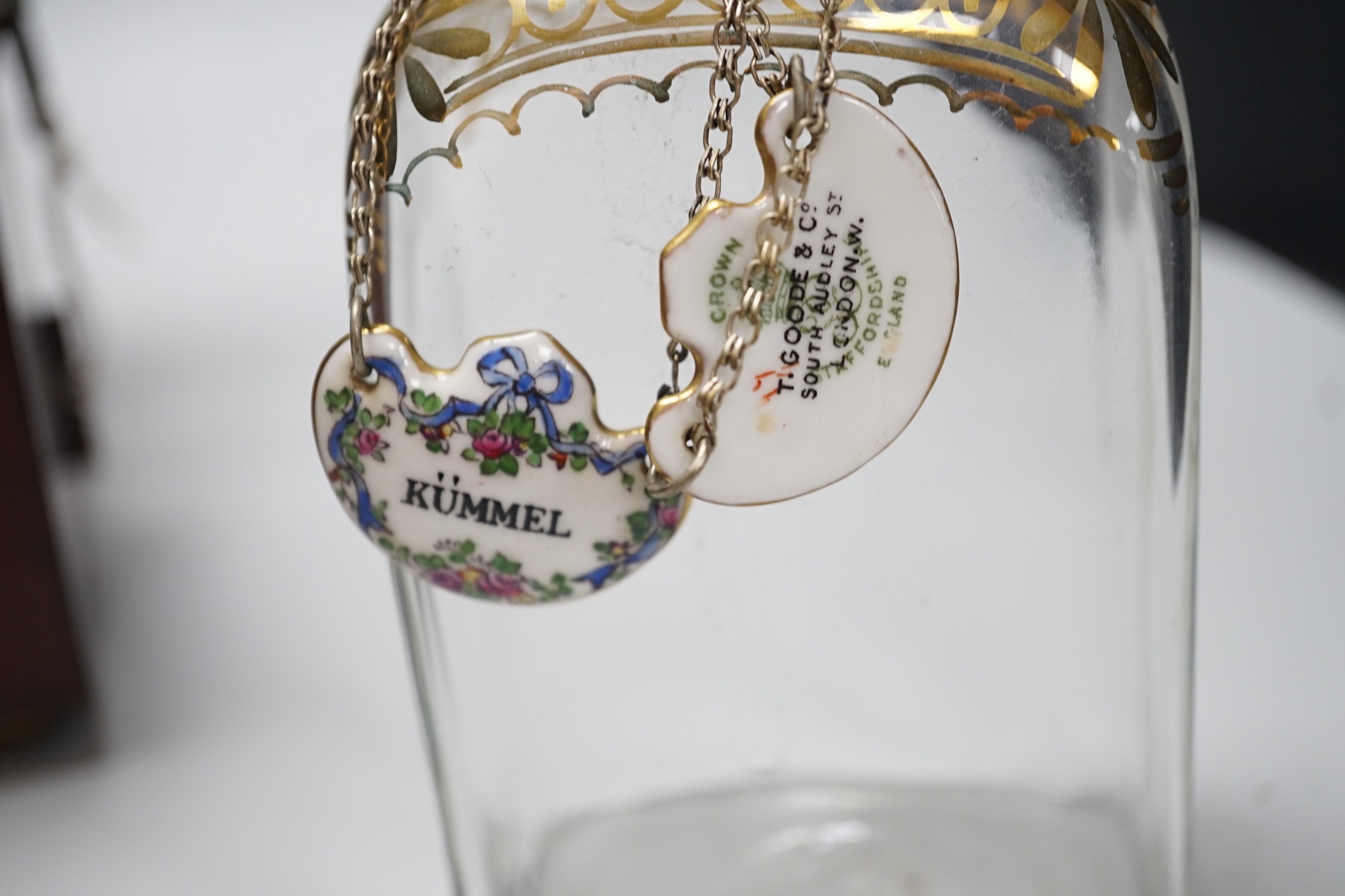 A George III inlaid mahogany decanter set with four gilt decorated decanters and two T.Goode & Co. enamelled wine labels, ‘BRANDY’ and ‘KÜMMEL’. 21cm tall